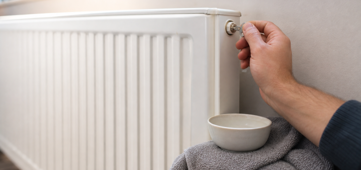Odzračevanje radiatorja s ključem in posodo pod ventilom.